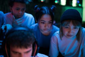Group of young people intensely focused on a gaming session in a dimly lit indoor environment.